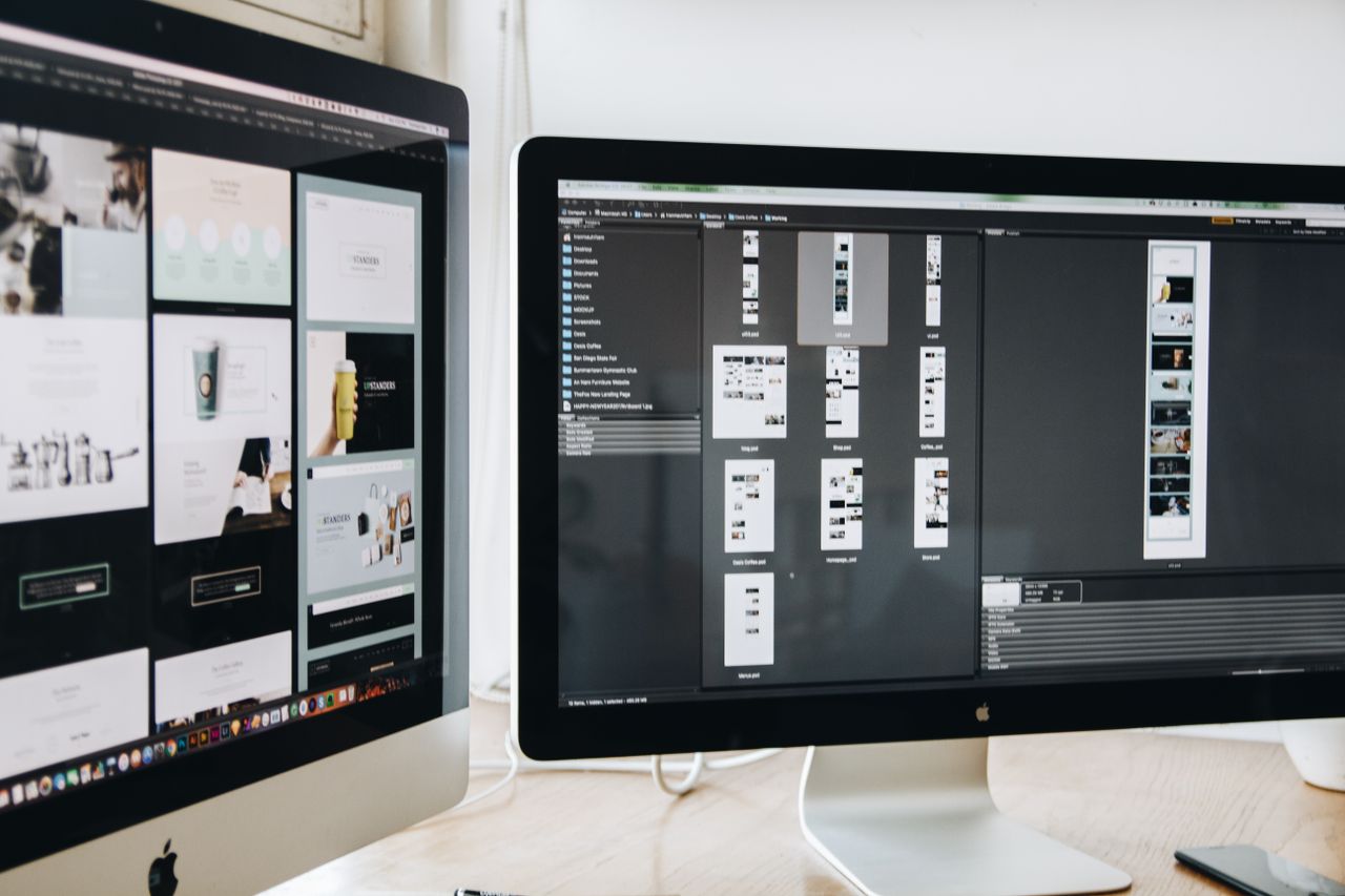 Un espace de travail moderne avec deux écrans d’ordinateur affichant des projets de conception web, mettant en avant la technologie et la productivité.